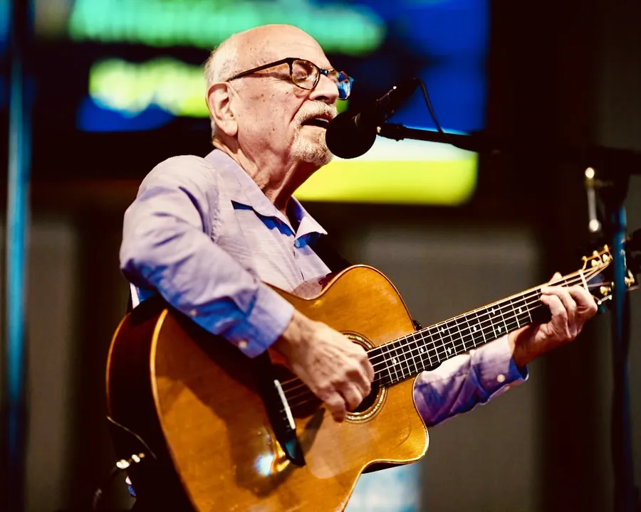 Ron singing and playing acoustic guitar on stage