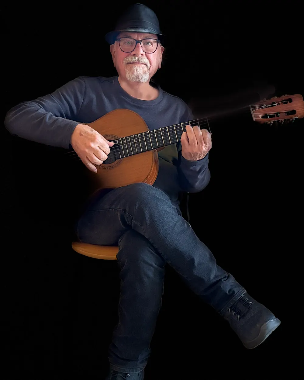 Ron Franklin seated with a classical guitar against a black background