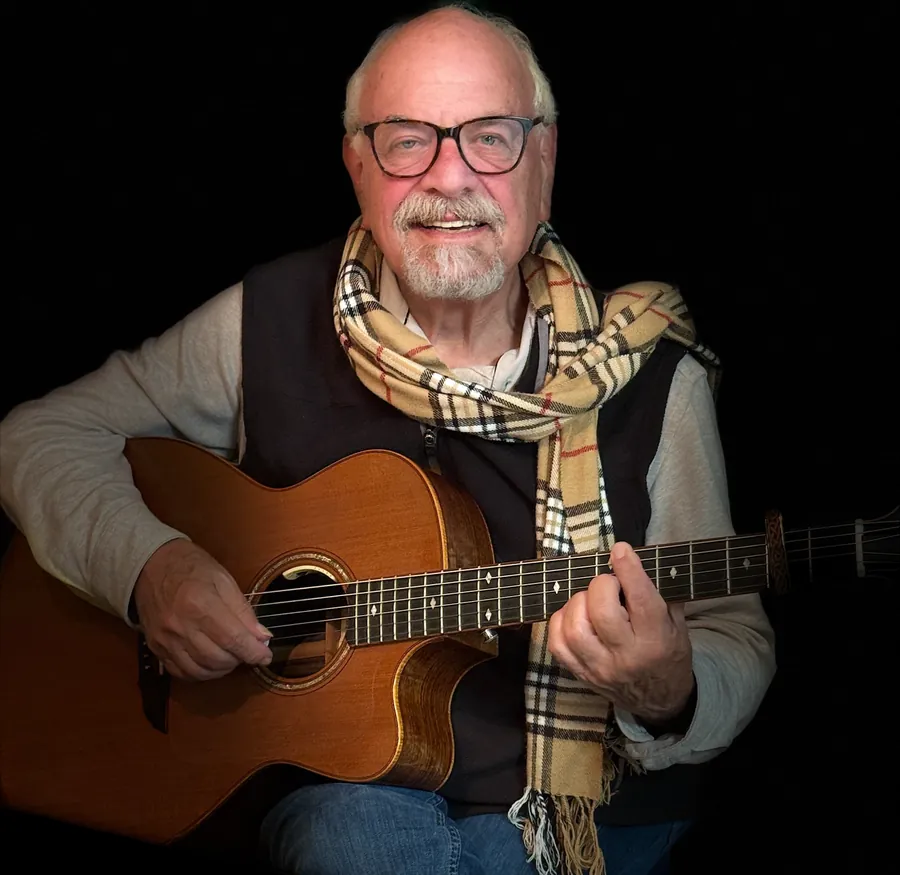 Ron smiling with an acoustic guitar